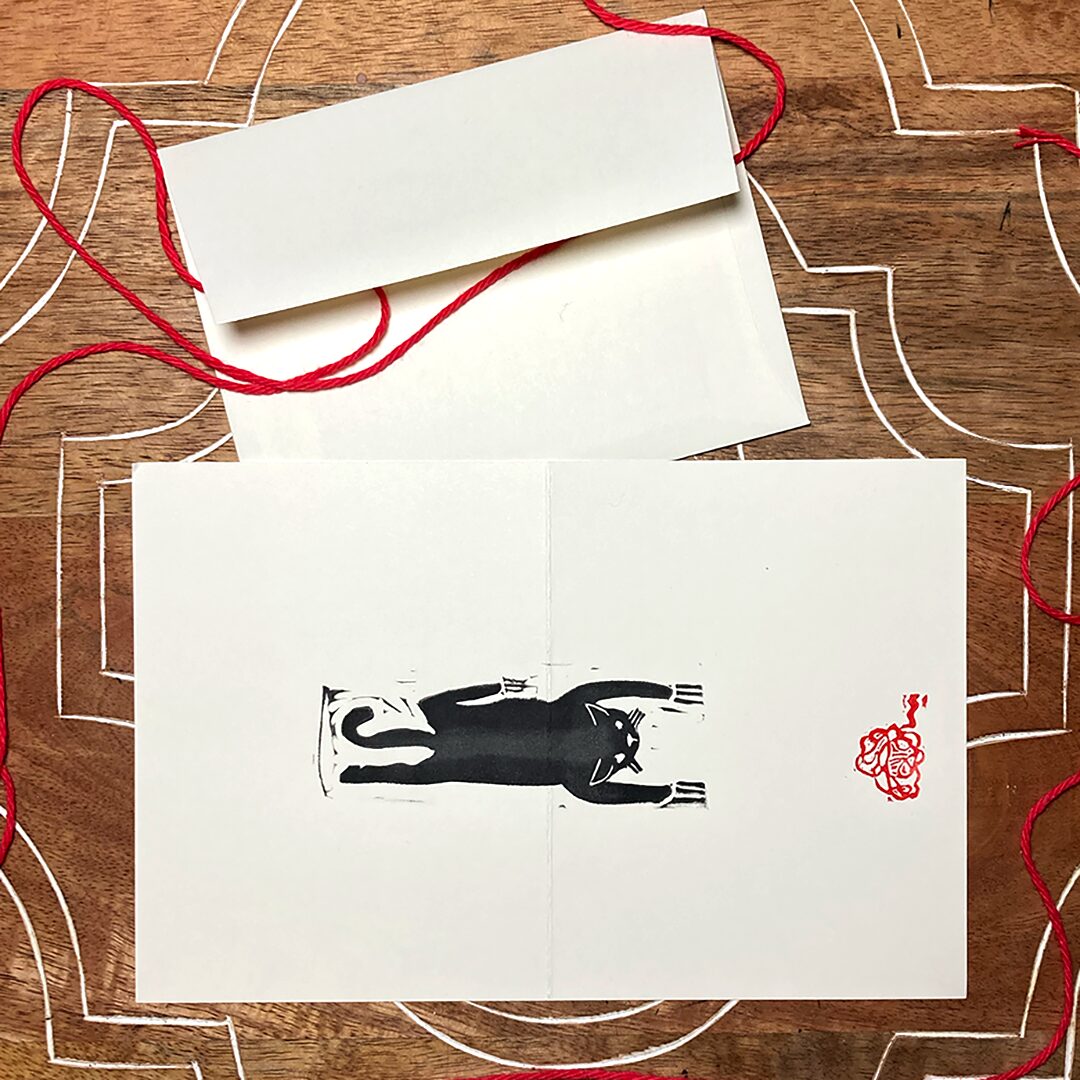 linocut card of a black cat with red yarn