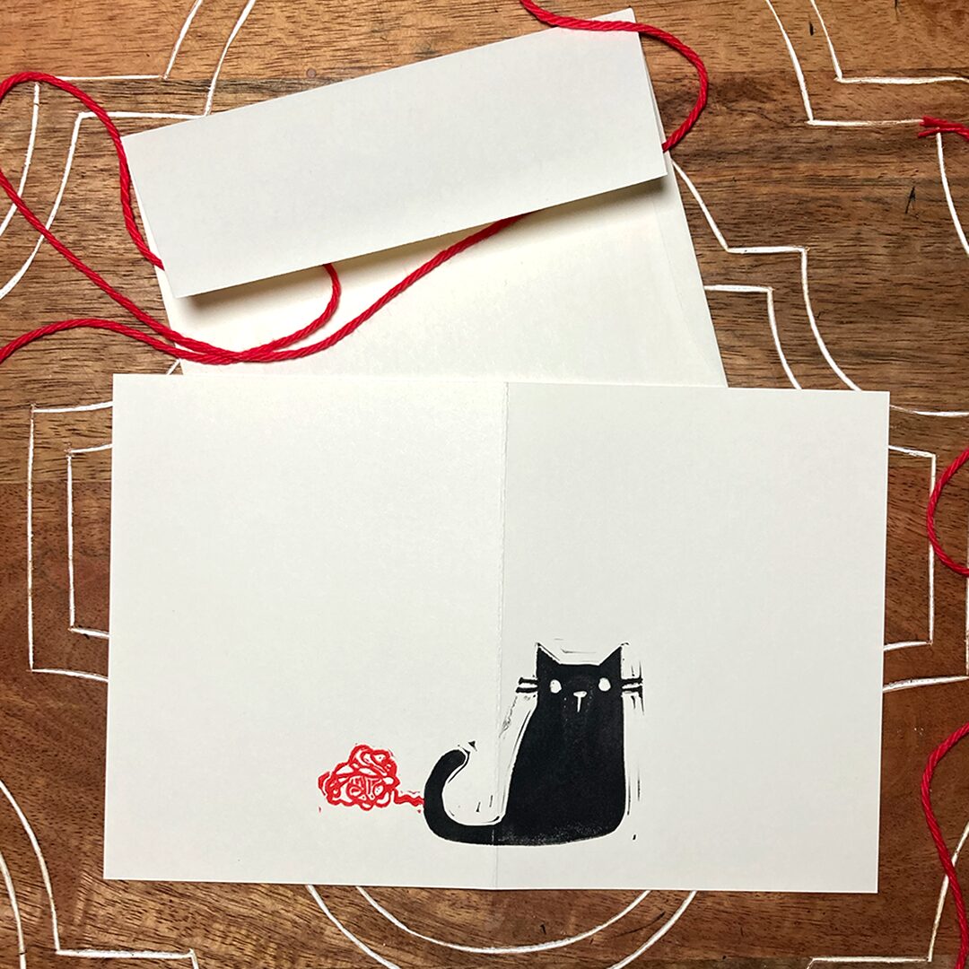 linocut card of a black cat with red yarn
