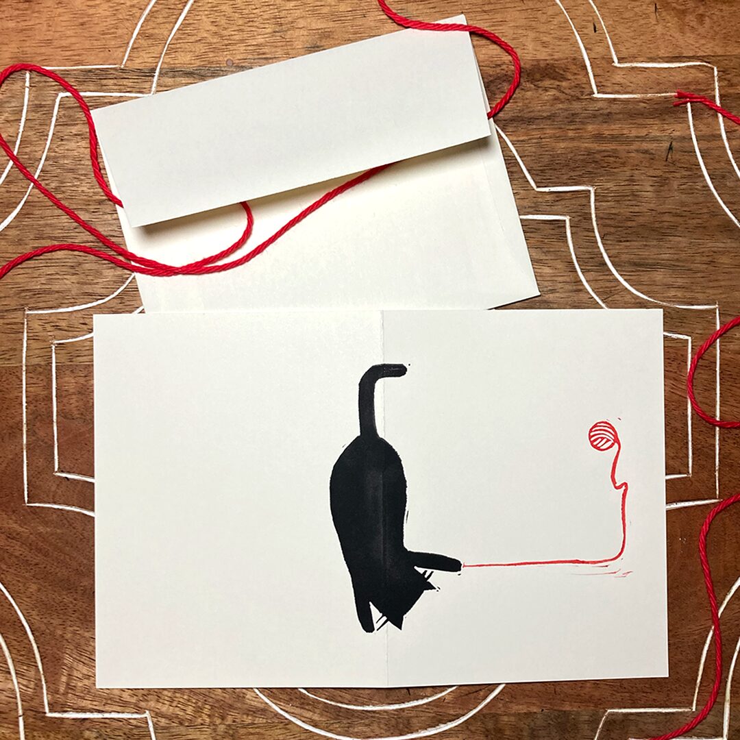 linocut card of a black cat with red yarn