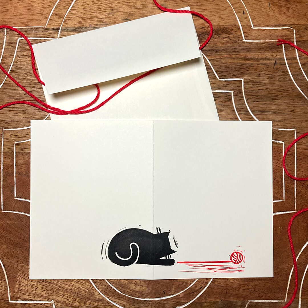 linocut card of a black cat with red yarn