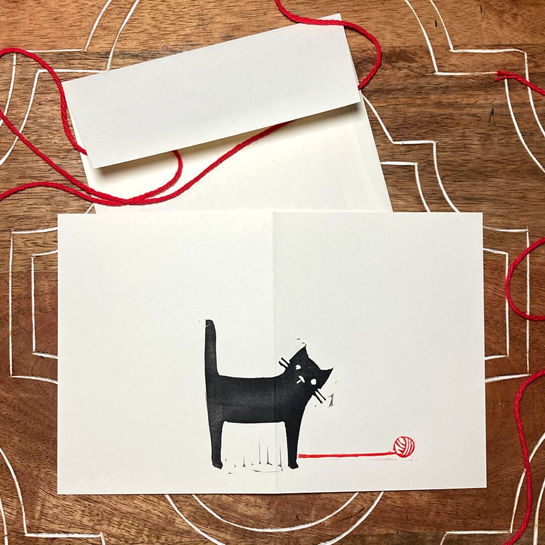 linocut card of a black cat with red yarn